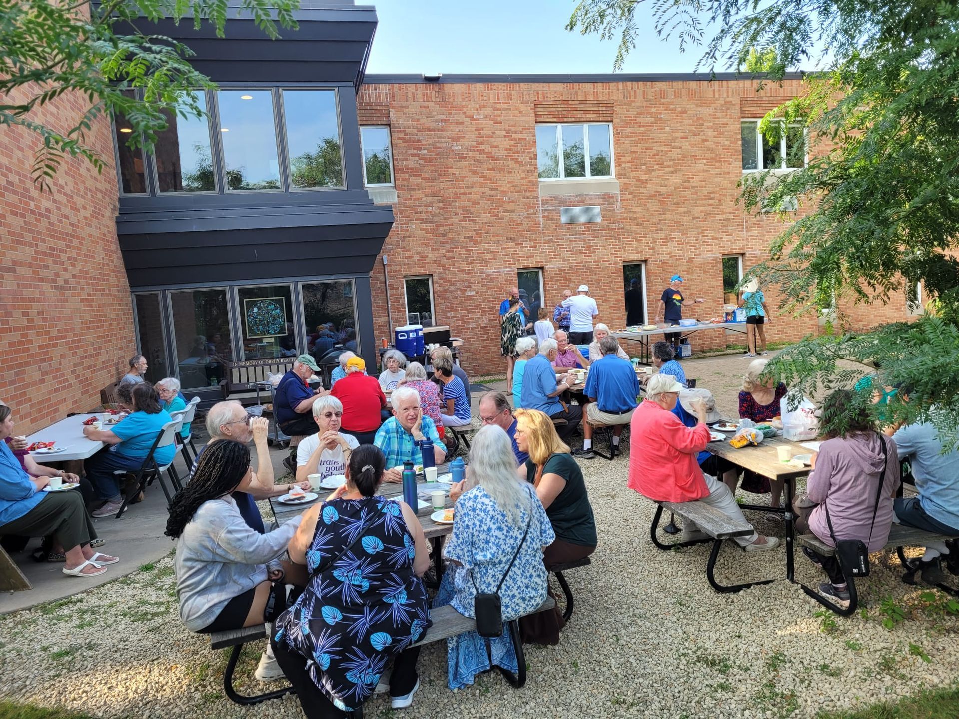 Neighbors and congregation sitting at picnic tables together.