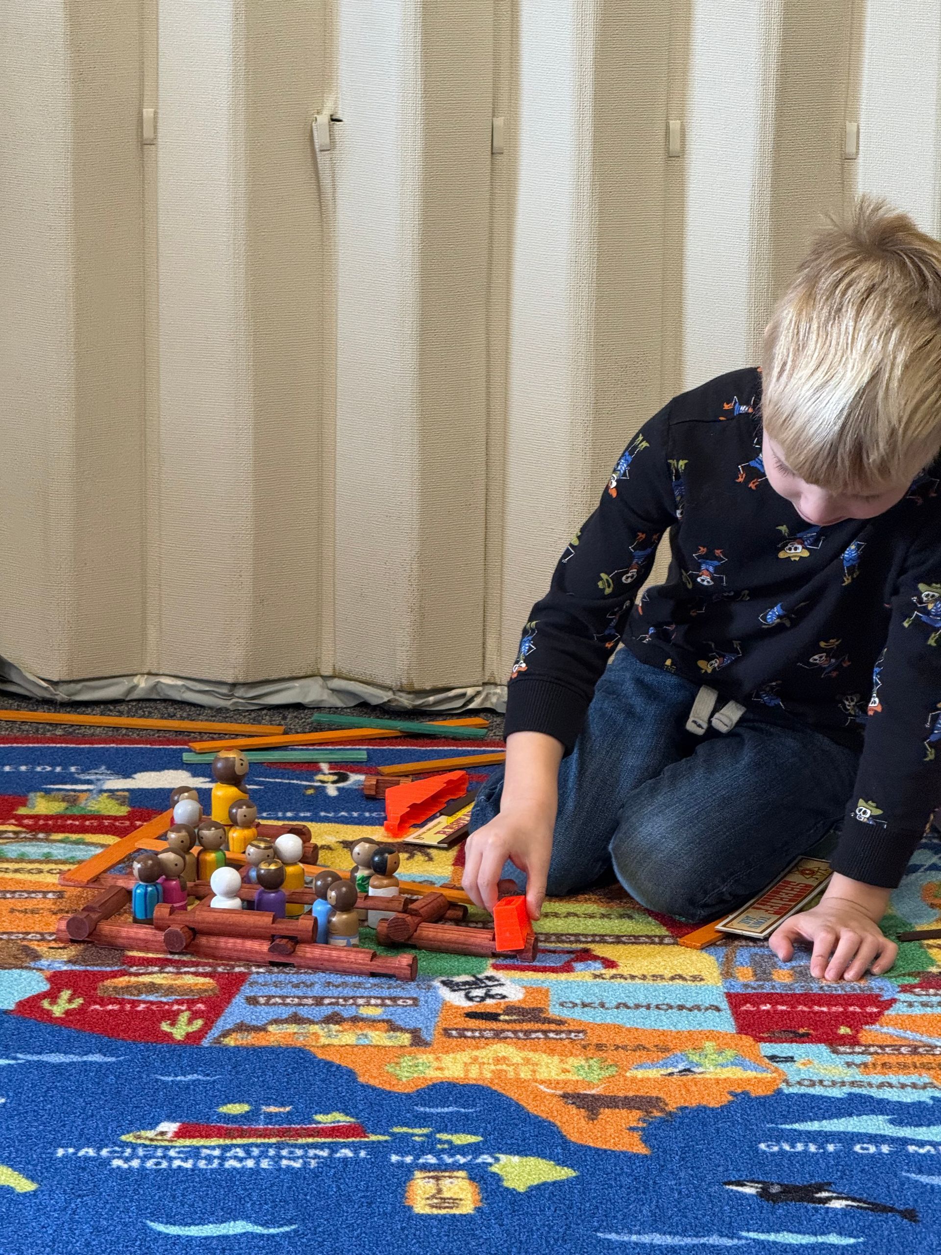 A group of people are sitting on the floor playing with toys.