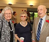 Three elderly people are standing next to each other in a room.