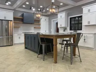 Modern kitchen with white cabinets, dark island, stainless fridge, and two bar stools