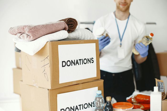 Boxes of donations with towels and a person holding items, assisting.