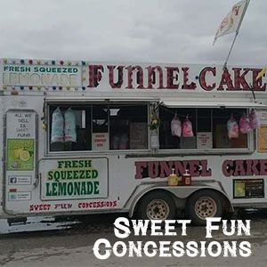 A white concession trailer with signs advertising funnel cake and fresh squeezed lemonade, branded 'Sweet Fun Concessions.'