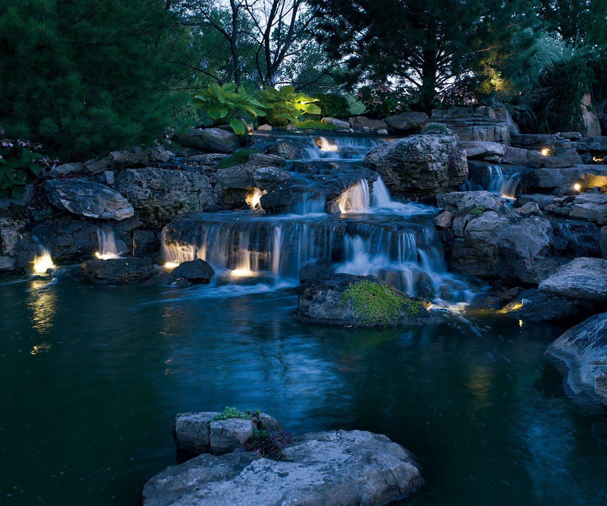 Waterfall cascade and landscape boulder lighting in Akron Ohio backyard pond