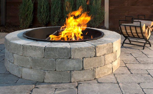 Wood burning stone fire pit made from Unilock wall block in Ohio backyard patio.