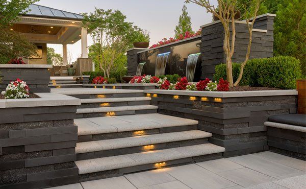Paver patio steps and retaining wall with lighting in Ohio home backyard landscape.