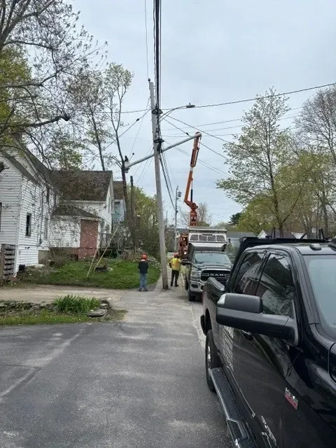 Utility crew using a bucket truck to repair overhead power lines on a residential street