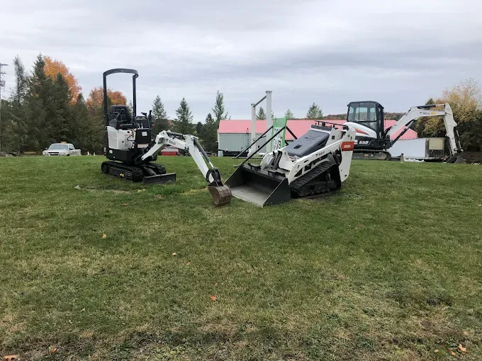 Overturned construction equipment on a grassy field near a park, with excavators and debris scattered around.