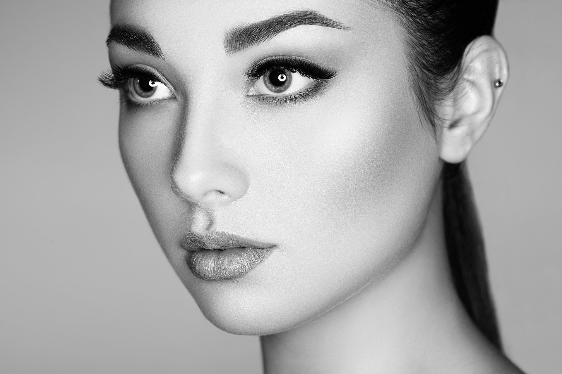 It is a black and white photo of a woman 's face with full eyelashes.