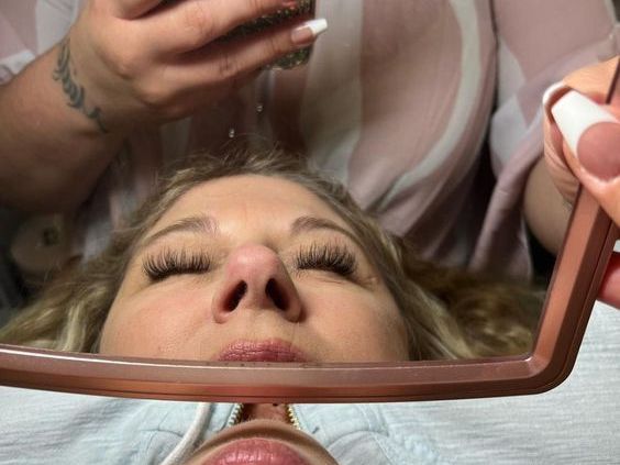 A woman is getting eyelash extensions at a salon.