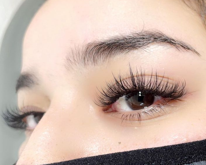 A close up of a woman's eye with long eyelashes extensions