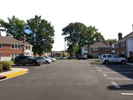 Apartment parking lot with parked cars, brick buildings, and trees on a sunny day