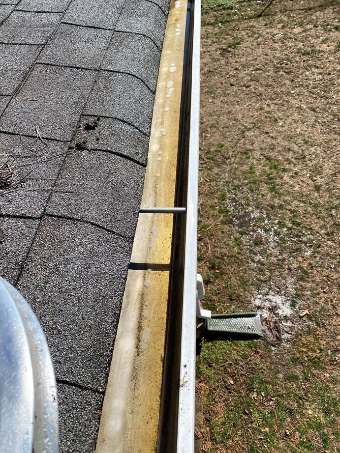 Gutter and roof edge with a black cable or rod spanning over the side of a building.