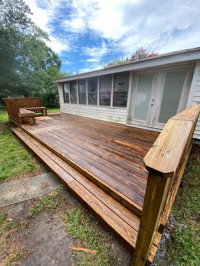 Wooden deck attached to a white house, with steps and a screened porch under a cloudy sky