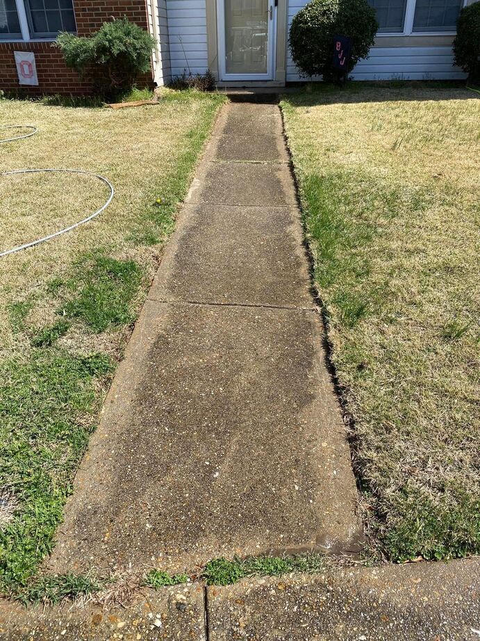 Concrete walkway leading from a lawn to a house front door