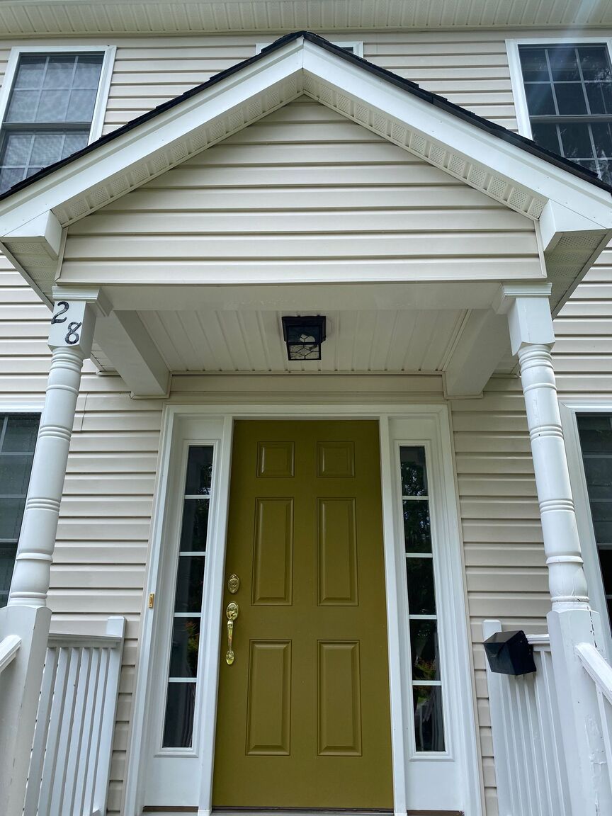 Front porch with yellow door, white siding, and narrow glass side panels