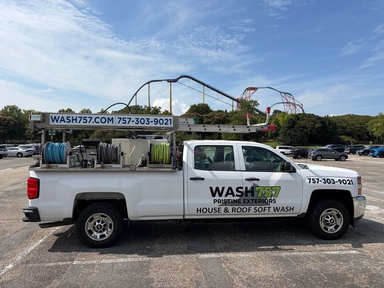 White WASH pest-control truck parked outdoors under a blue sky with a roller coaster in the background