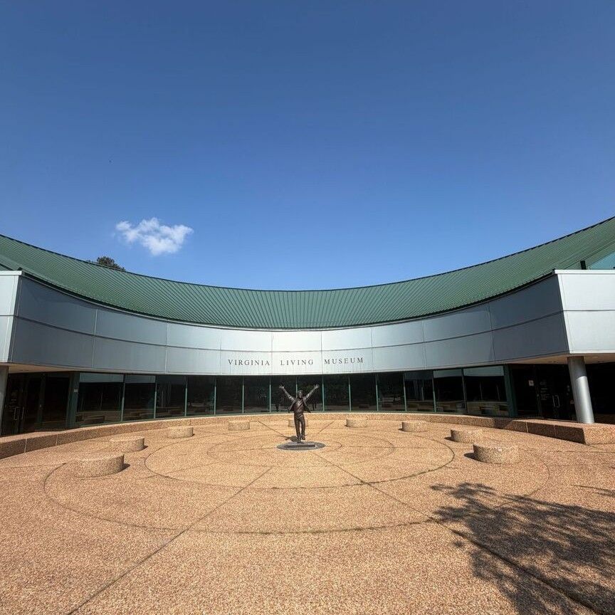 Modern building with curved green roof and circular courtyard under a clear blue sky