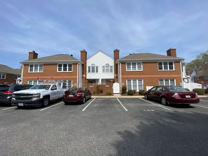 Apartment buildings with parked cars in front under a blue sky