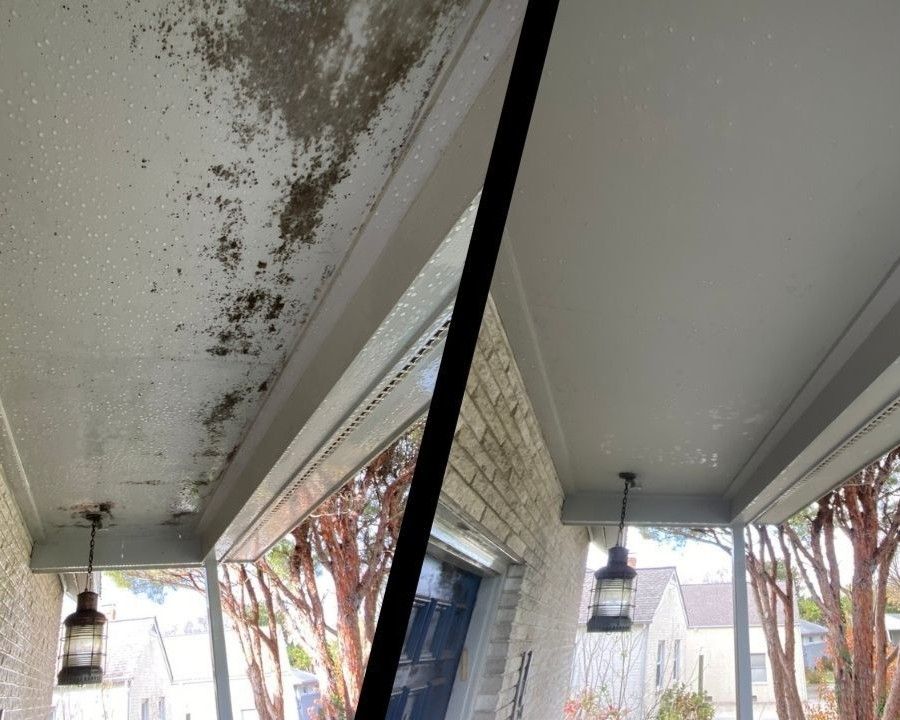 Water-damaged porch ceiling with dark mold stains above hanging lanterns and brick columns