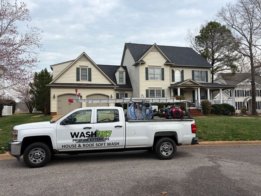 White utility truck labeled “WASH” parked on a suburban street in front of a large house.