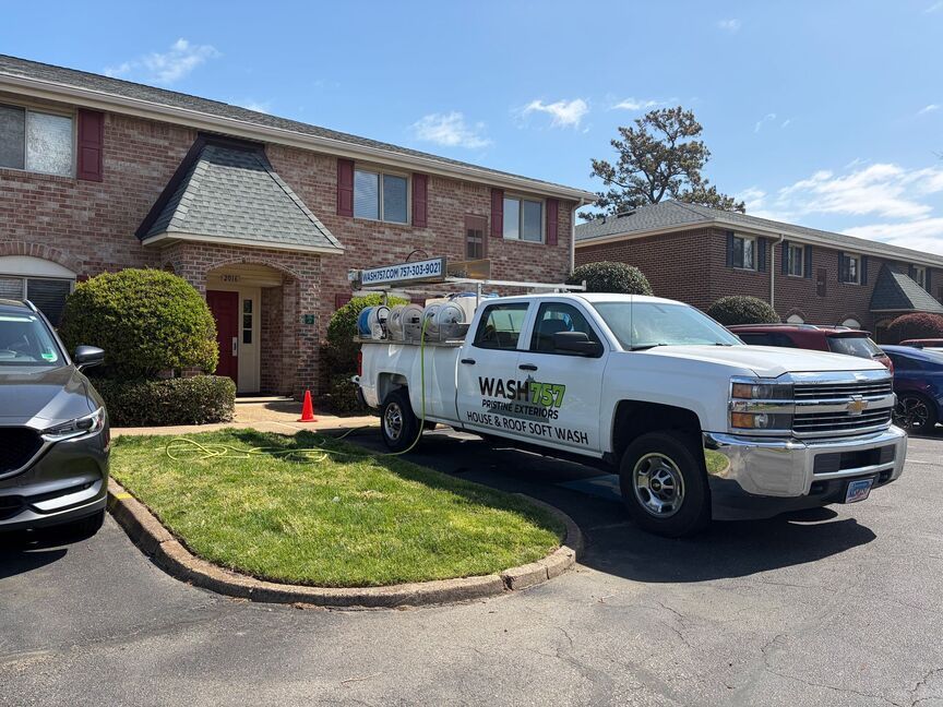 White work truck parked in front of a brick apartment building on a sunny day