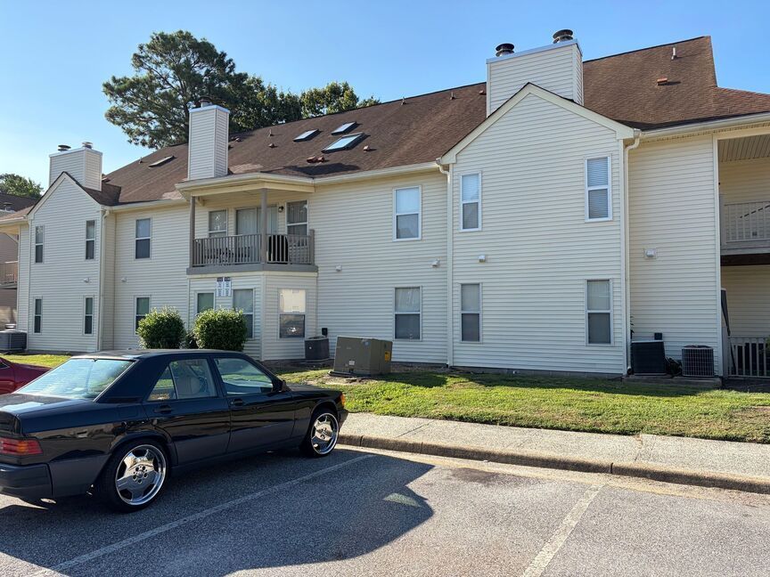 Apartment building exterior with parked black car on a sunny day