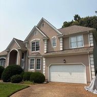 Two-story beige suburban house with a double garage, front lawn, and driveway