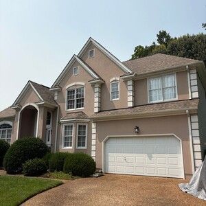 Two-story beige suburban house with a double garage, front lawn, and driveway