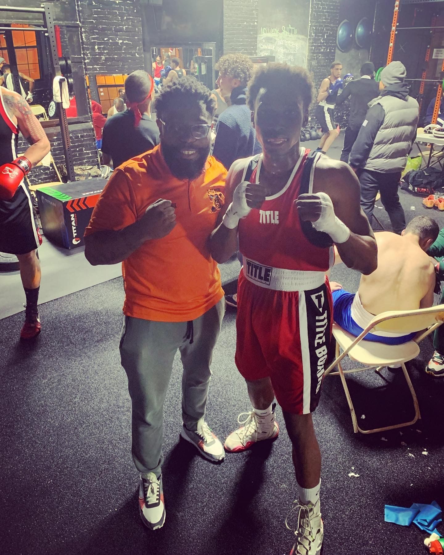Two boxers are posing for a picture in a gym