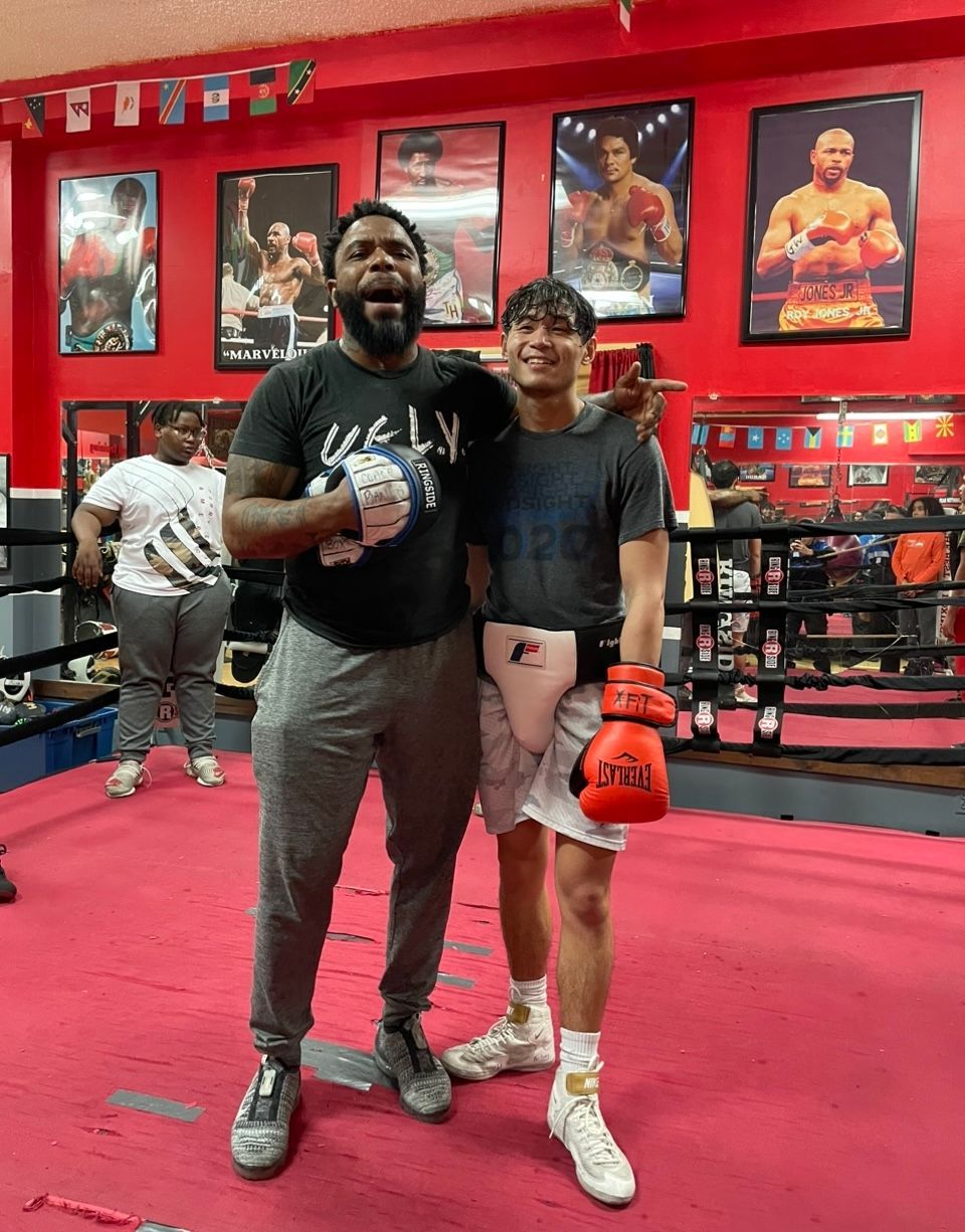 Two men are posing for a picture in a boxing ring.