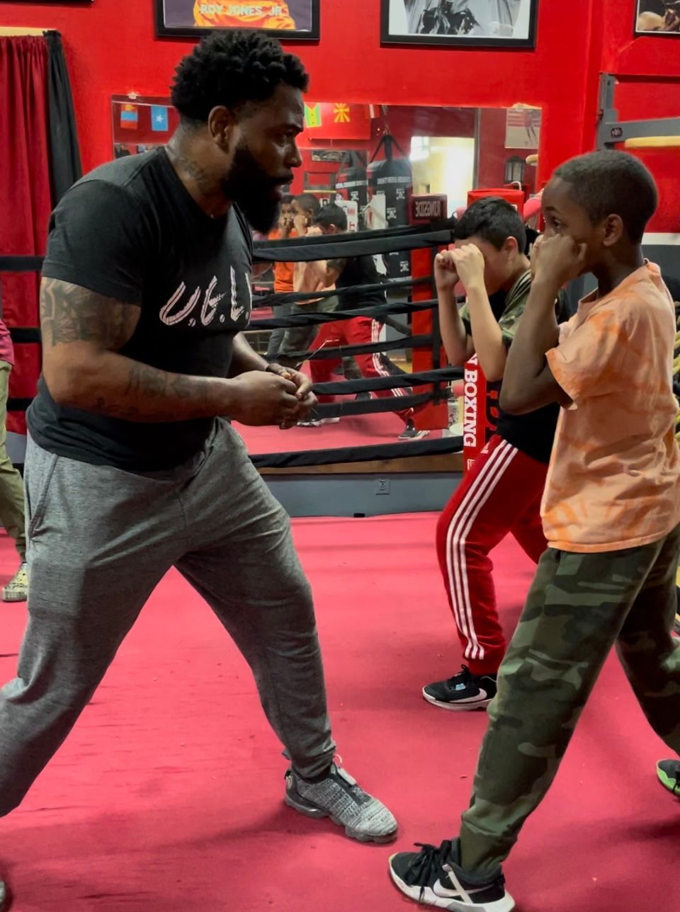 A man is teaching a young boy how to box in a boxing ring.