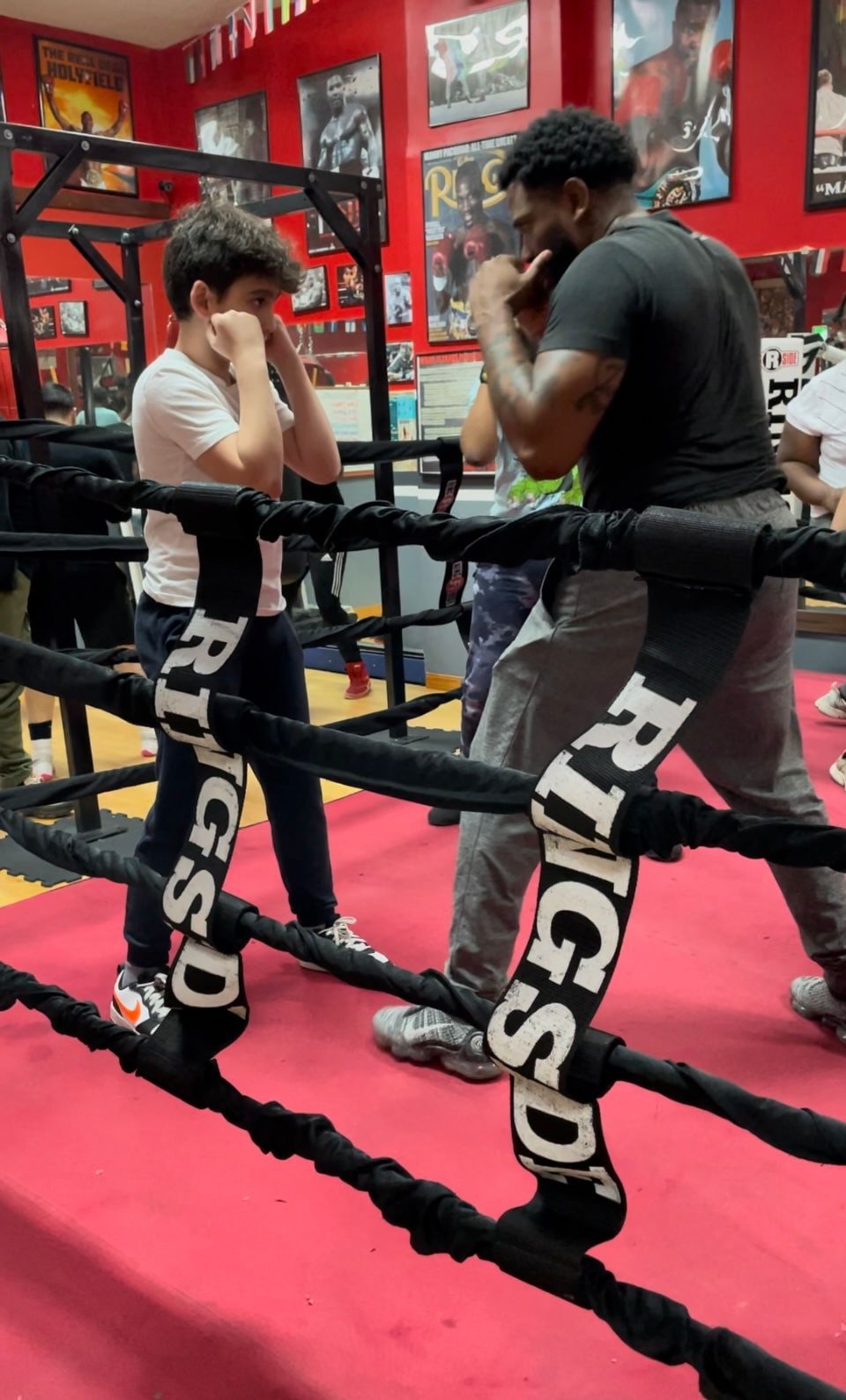 A man and a boy are boxing in a boxing ring.
