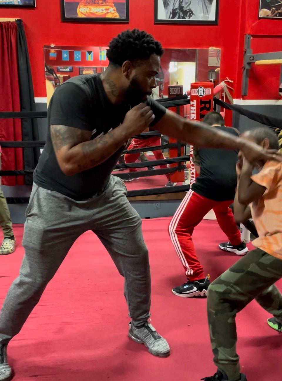 A man in a black shirt is boxing in a gym