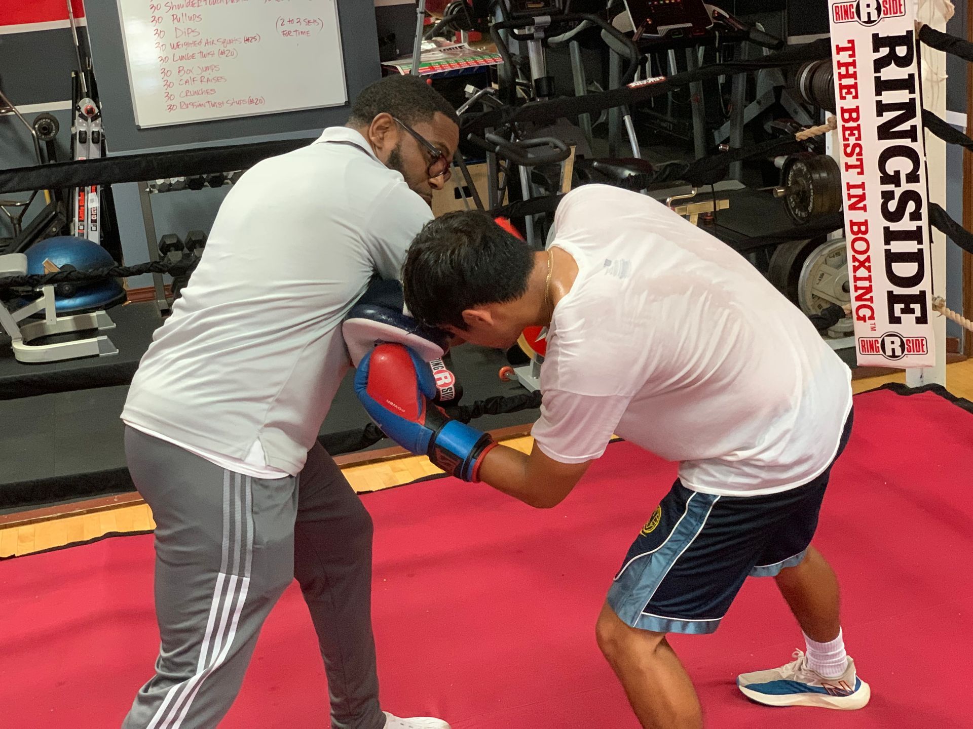Two men are boxing in a gym with a sign that says ringside