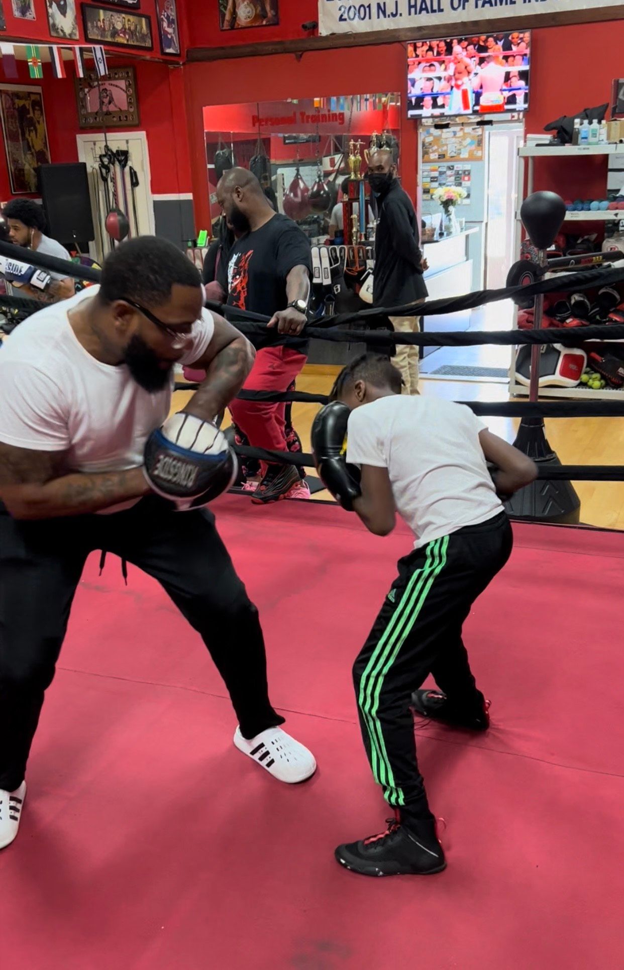 A man is teaching a young boy how to box in a boxing ring.