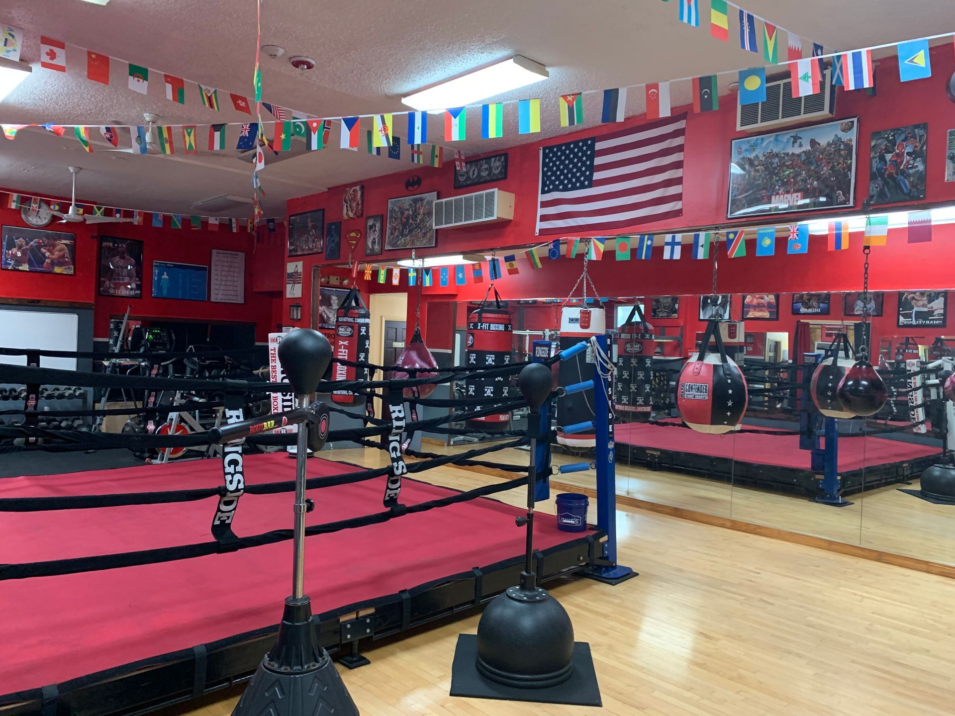 A boxing ring in a gym with flags hanging from the ceiling.