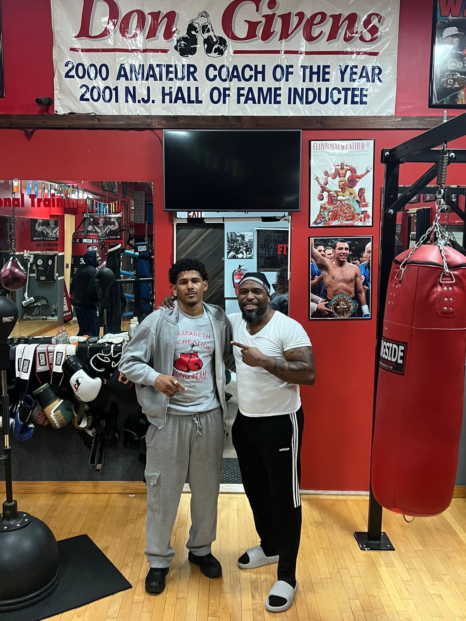 Two men are standing next to each other in a gym.