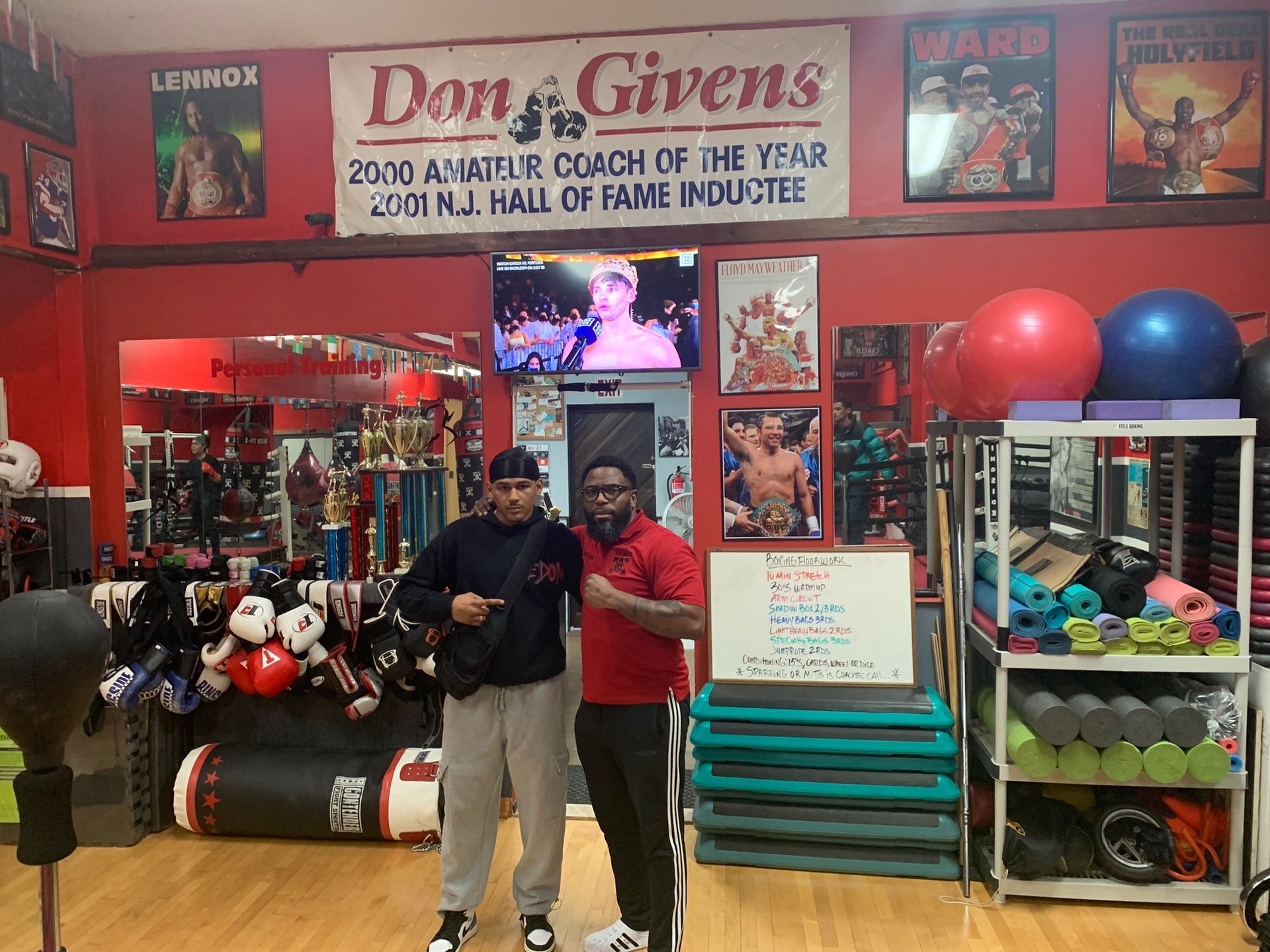Two men are standing in front of a sign that says don givens