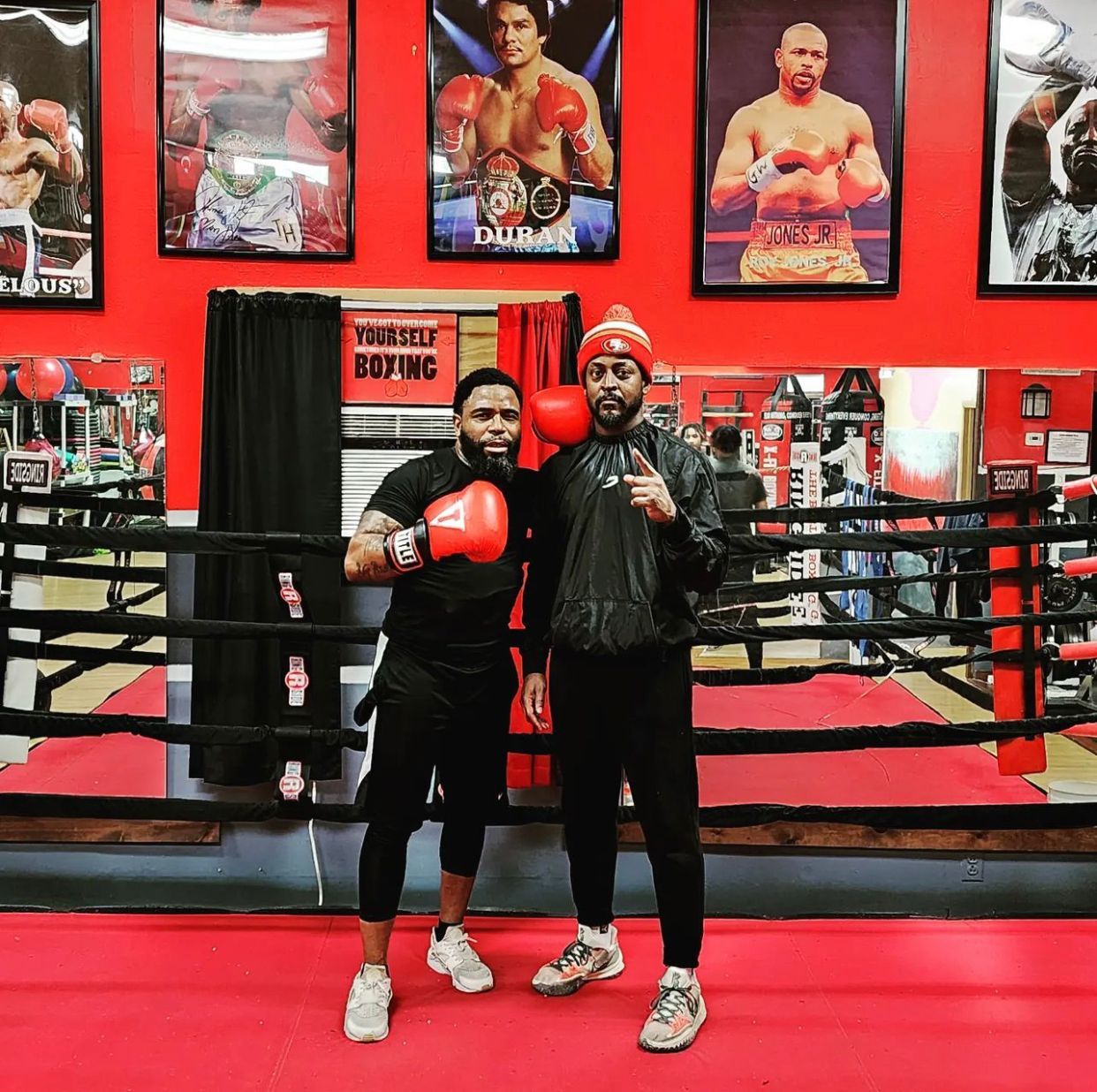 Two men are posing for a picture in a boxing ring.
