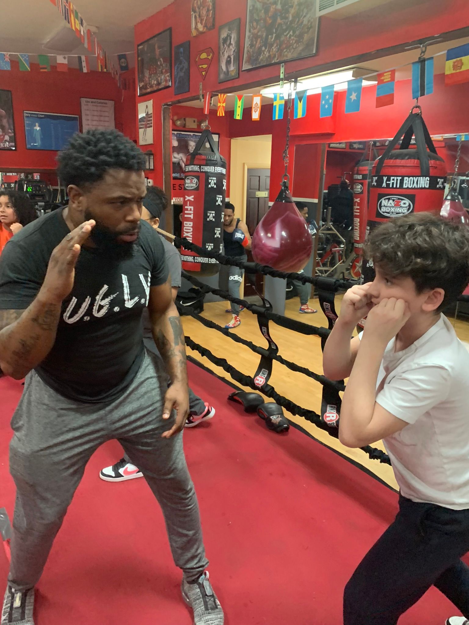 A man and a boy are boxing in a gym.