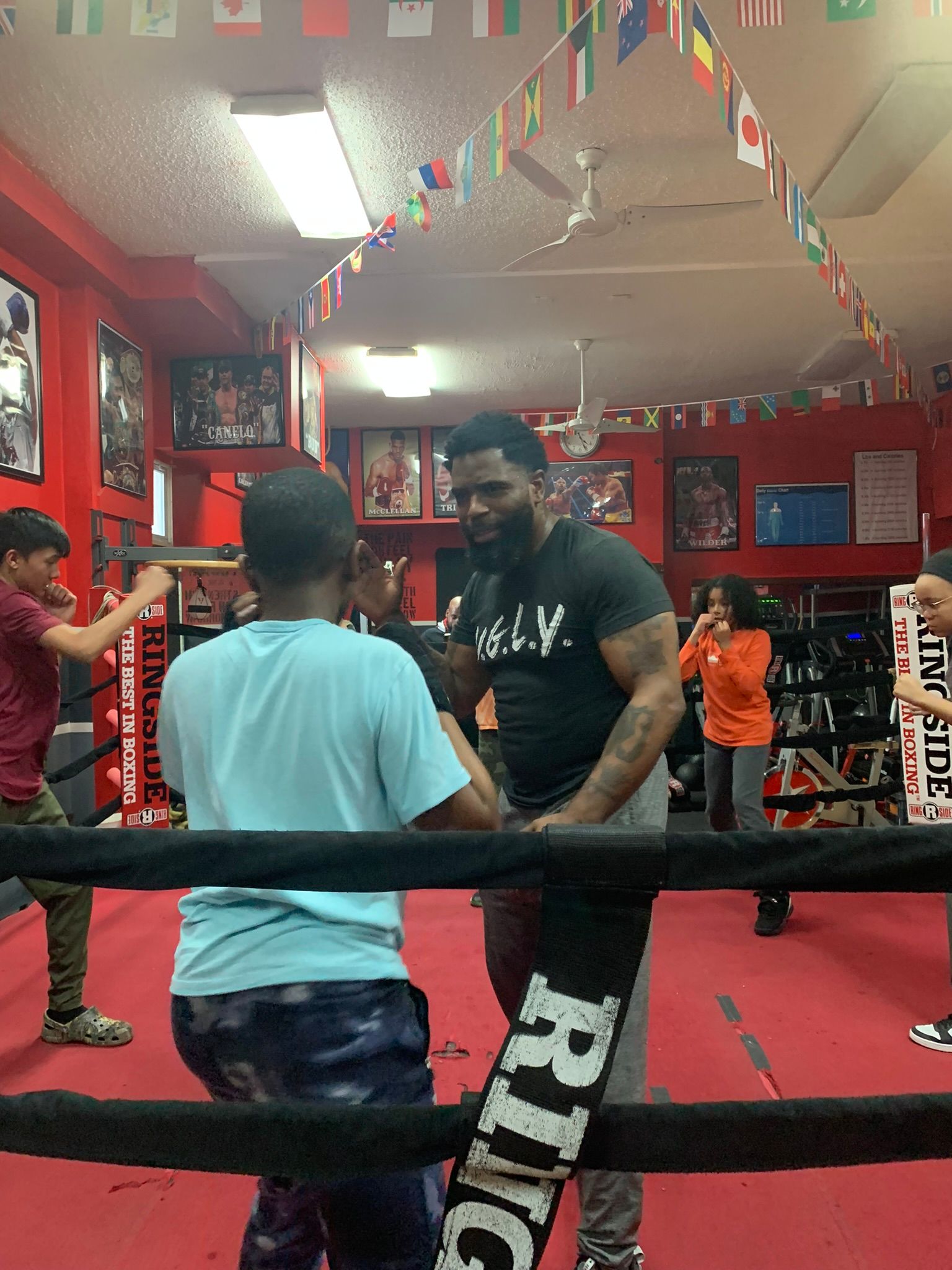 A man and a boy are standing in a boxing ring.