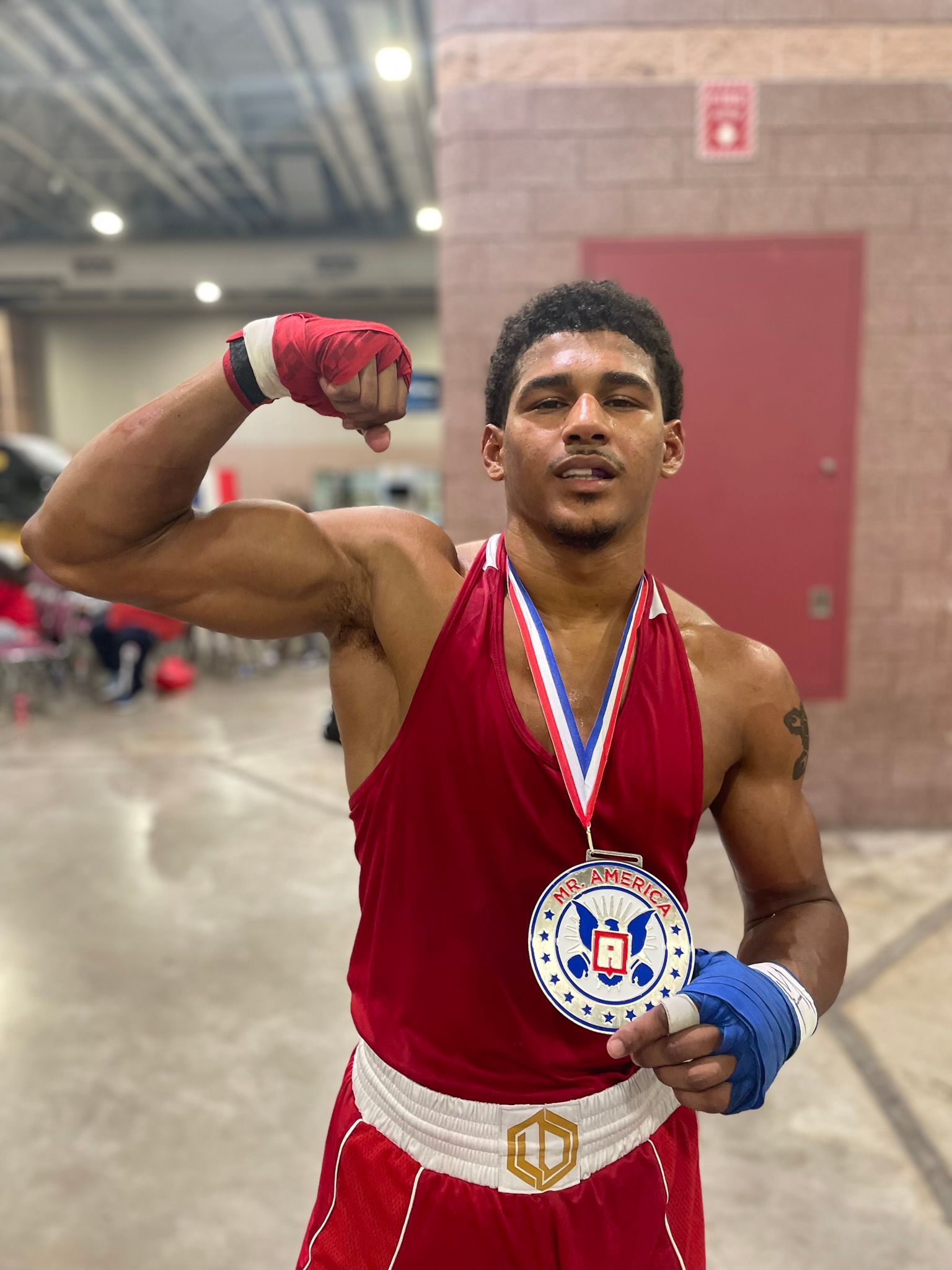 A boxer wearing a medal around his neck is flexing his muscles.
