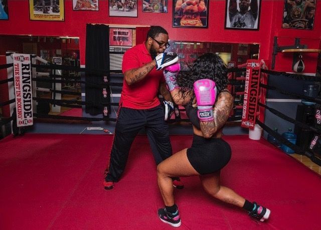 A man is teaching a woman how to box in a boxing ring.