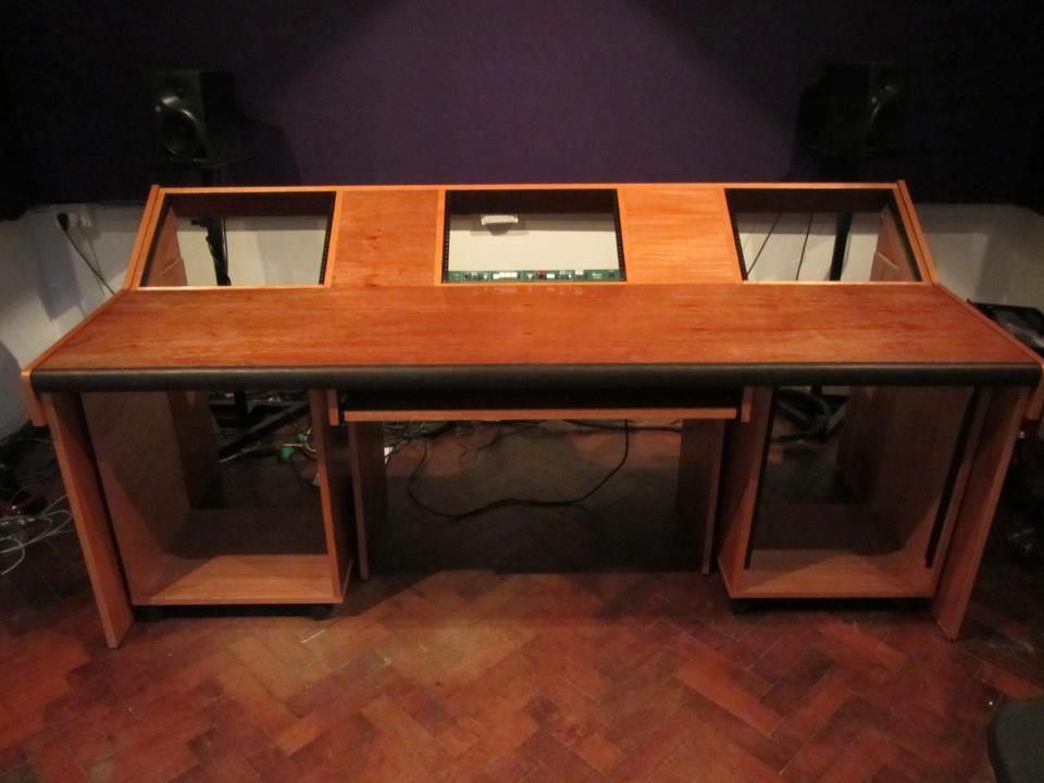 Escritorio de estudio de grabación de madera con compartimentos para equipos, controles y un estante para teclado.