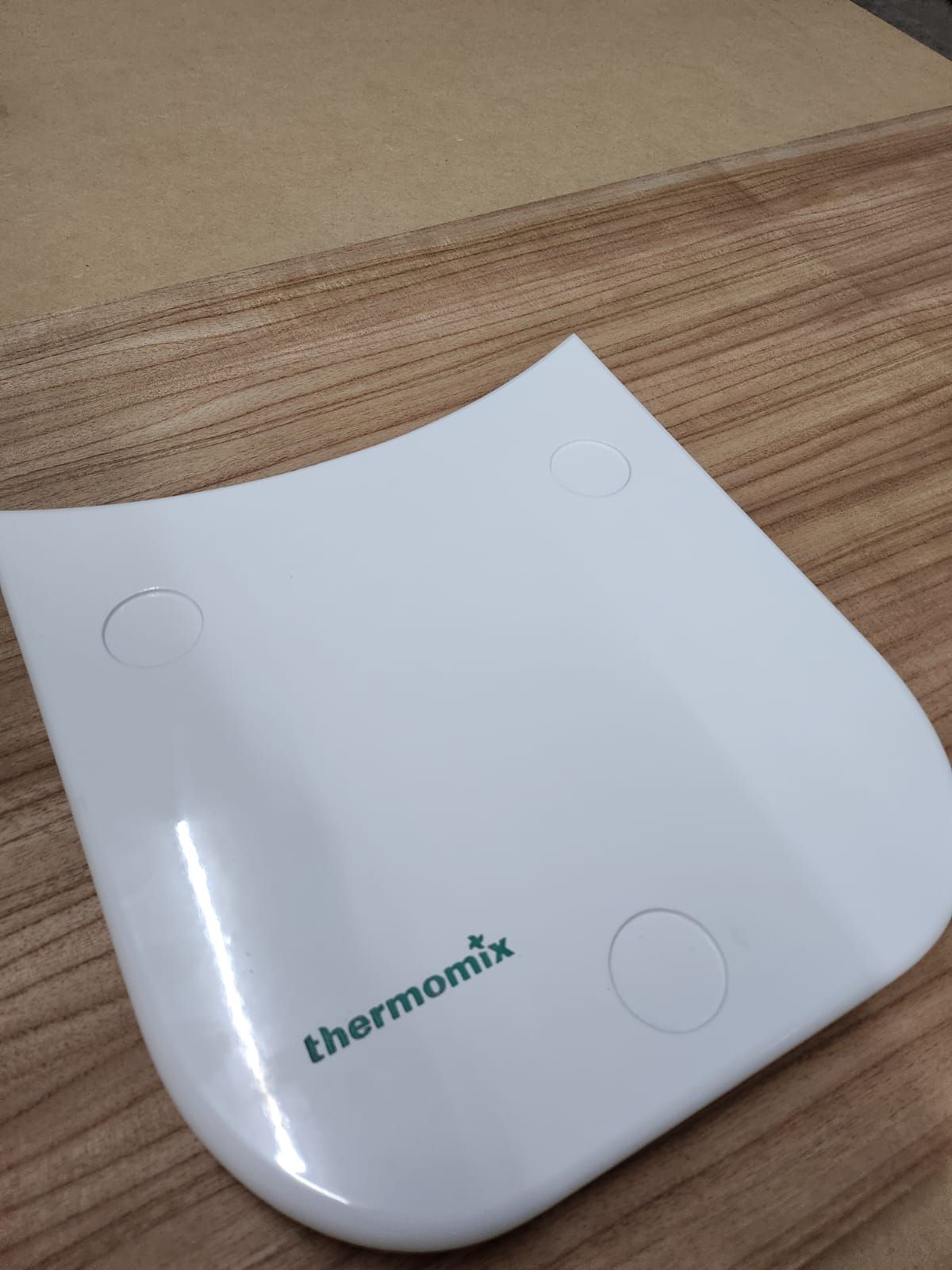 Escala Thermomix blanca sobre superficie de madera, con logo y hendiduras circulares.
