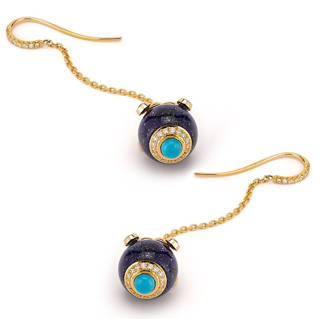 A pair of earrings with turquoise and diamonds on a gold chain