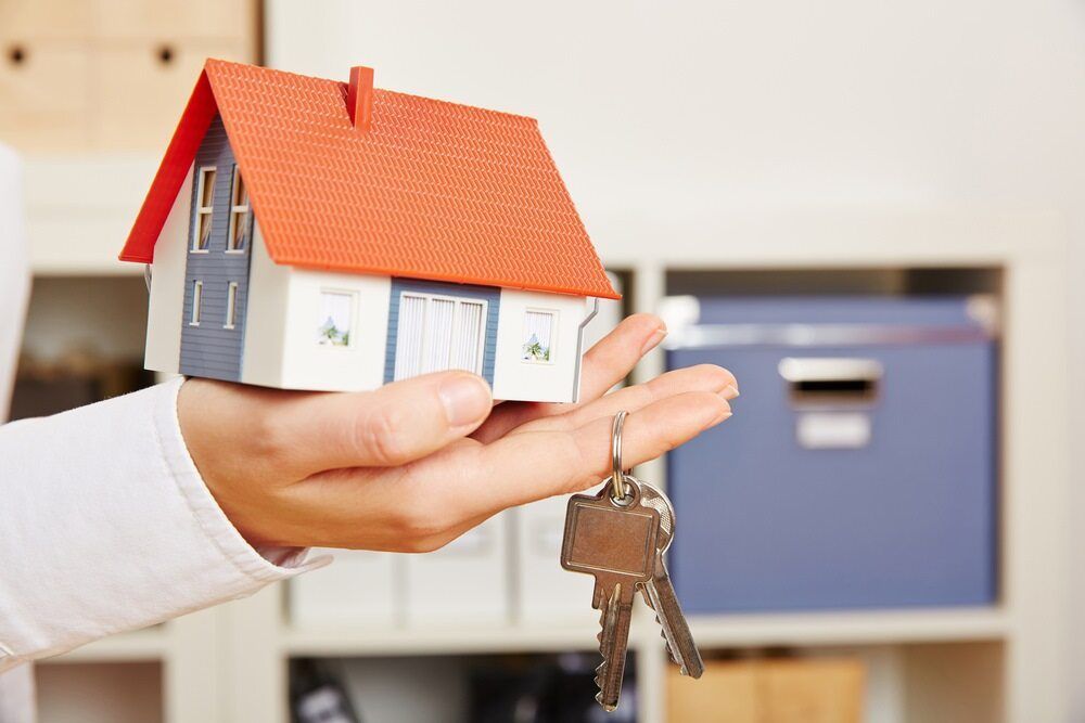 A Person is Holding a Model House and Keys in Their Hand — Key2 Conveyancing In Pacific Palms, NSW