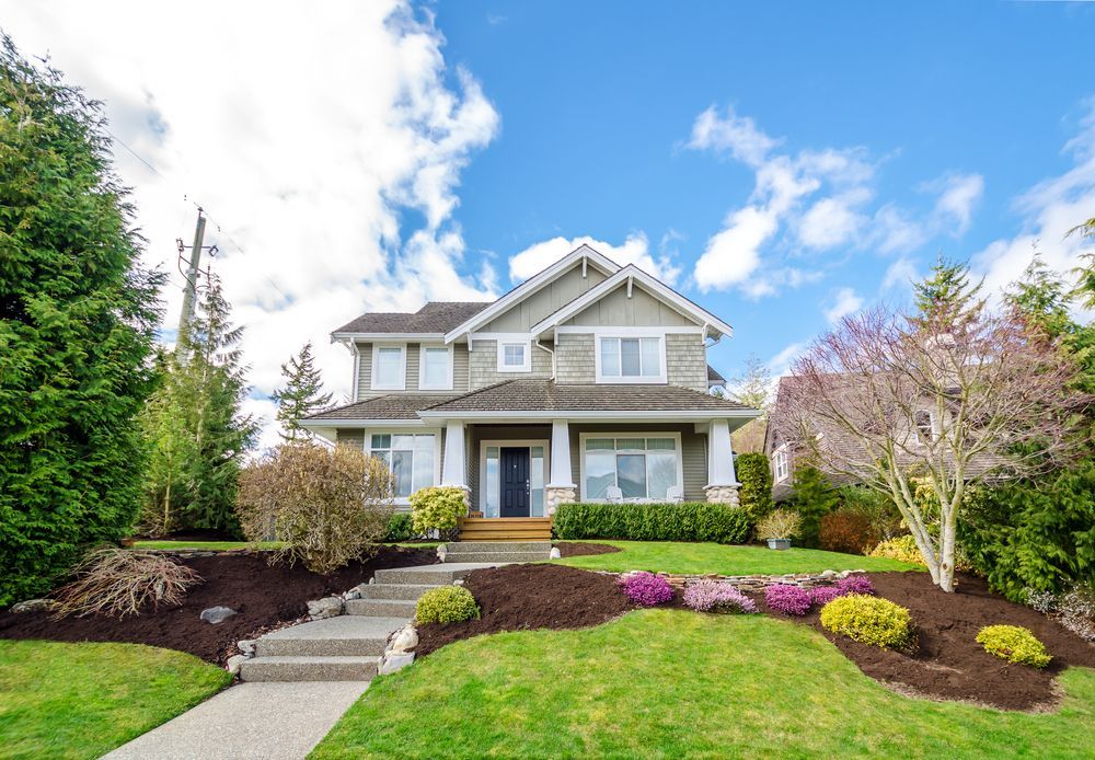 A Large House With a Lush Green Lawn and Flowers in Front of It — Key2 Conveyancing In Diamond Beach, NSW