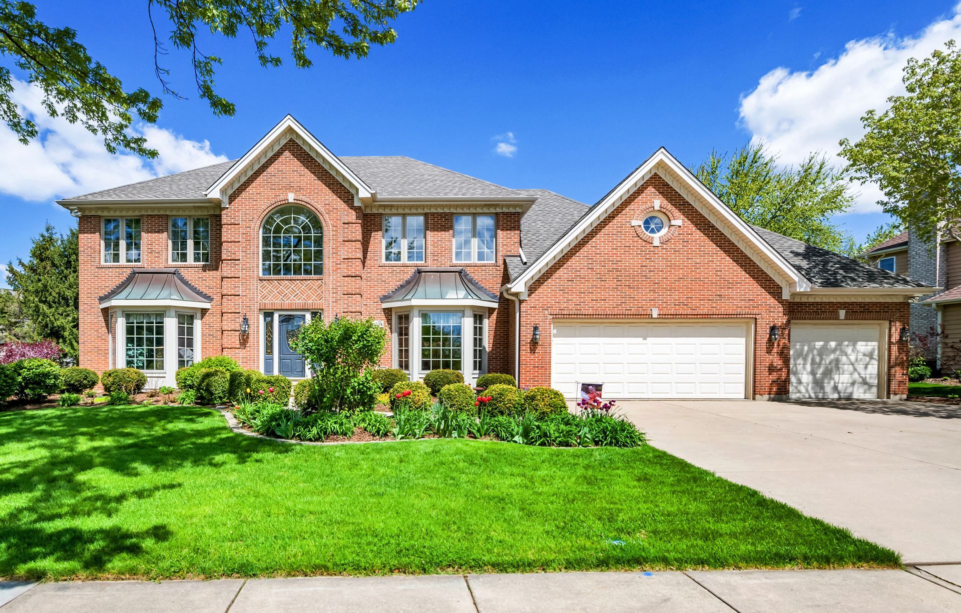 A Large Brick House With a White Garage Door and a Lush Green Lawn — Key2 Conveyancing In Hallidays Point, NSW