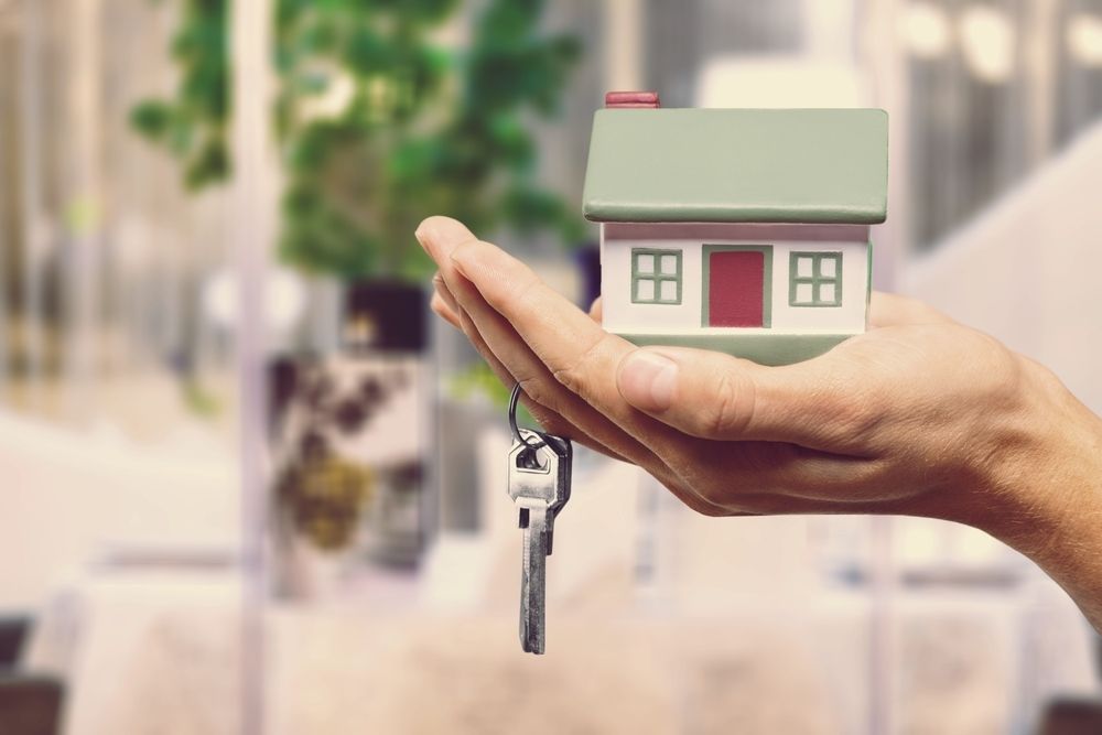 A Person is Holding a Model House and Keys in Their Hand — Key2 Conveyancing In Forster, NSW
